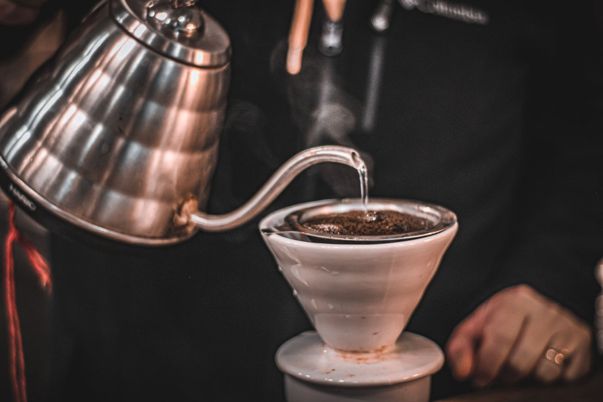 Pouring hot water over ground coffee in a pour-over brewer